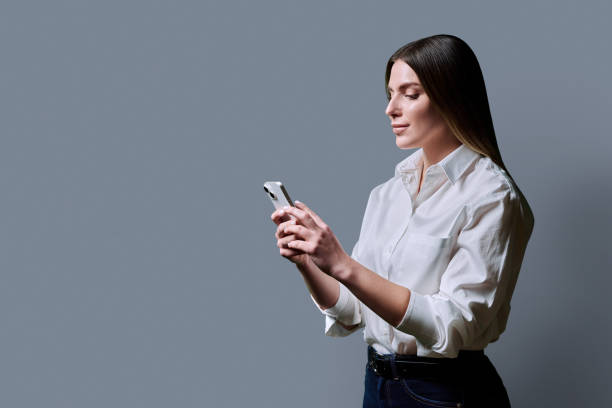 istock Profile view, young beautiful woman using mobile phone on grey background 2191232590