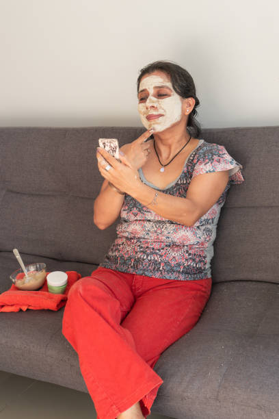 istock Woman applying face mask at home checking herself on smartphone 2191245253