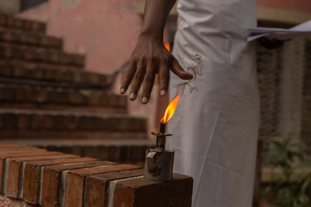 A hand near a small lighted lamp (Lamp Tèt Gridap)