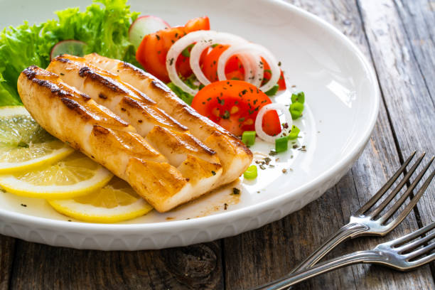 istock Fried calamari steak with lemon and fresh vegetables on wooden table 2191273645
