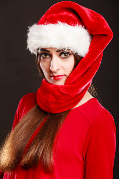 Christmas winter happiness concept. Woman wearing santa helper hat portrait on dark black background