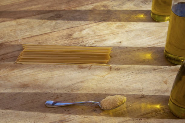 spaghetti and parmesan cheese on a wooden table with reflections through olive oil bottles