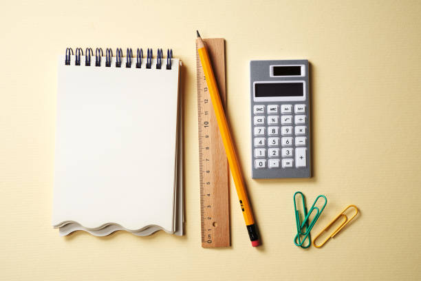 Calculator and spiral notebook, pencil ,ruler isolated on yellow background