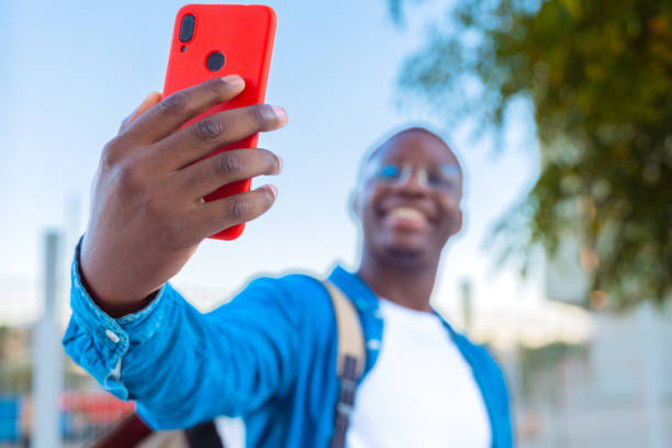 istock Young man taking a selfie outdoors with a red smartphone, smiling 2191290379