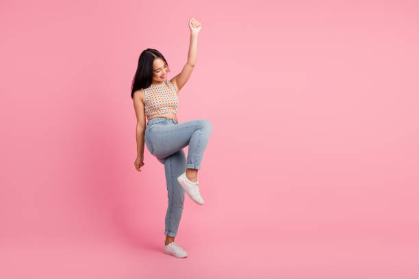 istock Happy young woman in stylish outfit dancing joyfully against a pink background 2191293708