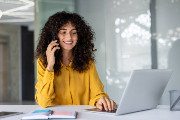 istock Cheerful professional using phone and laptop at work in office setting 2191293759