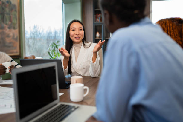 istock Mixed group of business people sitting around a table and talking 2191293804