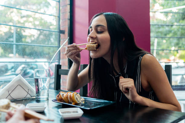 istock Young woman eating on a sushi bar 2191294605