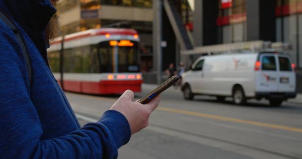 istock Pedestrian checking smartphone as tram approaches on city street. Image captures modern reliance on digital tools for public transport schedules and urban mobility convenience, vibrant city life. 2191296915