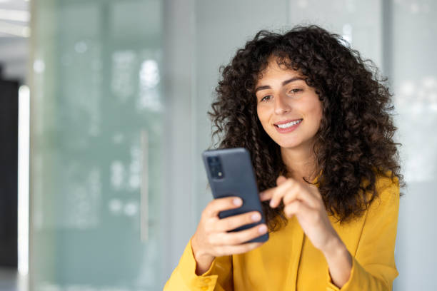 istock Smiling woman in yellow shirt uses smartphone for communication while enjoying modern technology indoors 2191299367