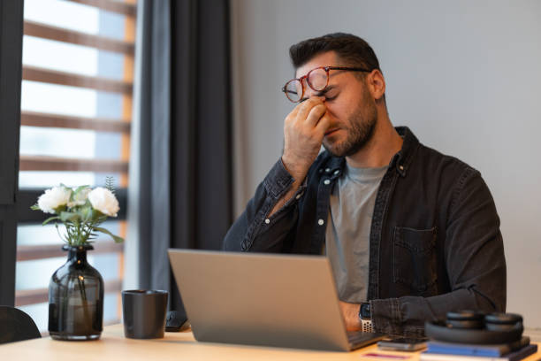 istock Stressed businessman rubbing his nose bridge while working from home 2191300732