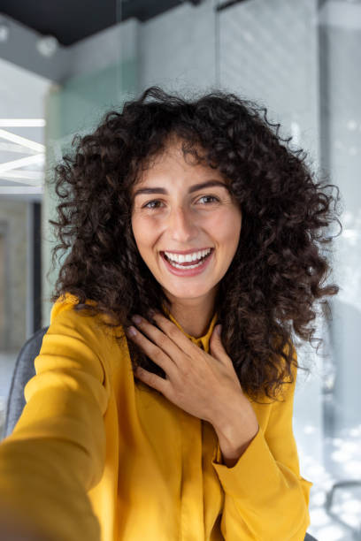 istock Cheerful woman taking a selfie with smartphone in modern office setting 2191301873