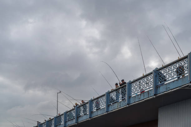 Istanbul, Turkey - November 11, 2024: Fishermen lined up on The Galata bridge in Istanbul