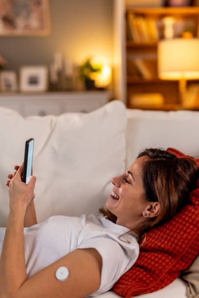 istock Woman Smiling While Using Smartphone Relaxing on Sofa Wearing Medical Device 2191304372
