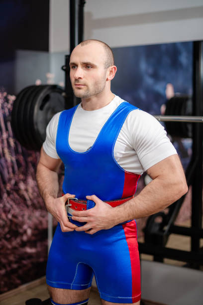 Dedicated athlete wearing lifting gear tightening his belt before engaging in powerlifting training.