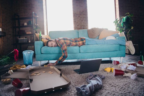 istock Young man relaxing on sofa in living room amidst casual clutter, enjoying a weekend break 2191308925