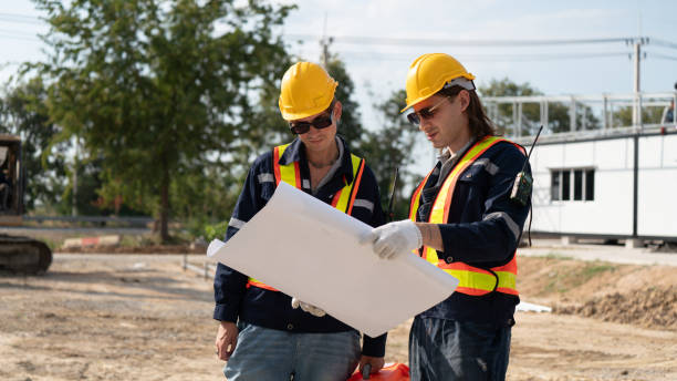 istock Caucasian white civil engineer, architect, or construction worker is wearing a safety suit while inspecting building construction on site and verifying blueprints or drawing plans. 2191308940