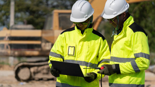 istock Caucasian white civil engineer, architect, or construction worker is wearing a safety suit while inspecting building construction on site and verifying blueprints or drawing plans. 2191308976