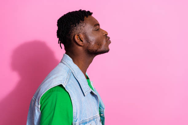 istock Young stylish man posing with a playful expression against a vibrant pink background, showcasing trendy fashion 2191309338