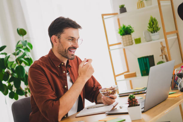 istock Young man enjoying a healthy snack while working on his laptop at home in a bright, modern interior 2191310708