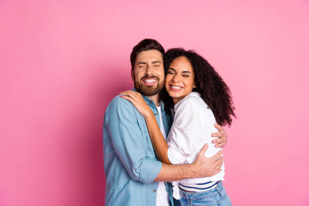 istock Couple smiling cheerfully while embracing against a vibrant pink background 2191311286