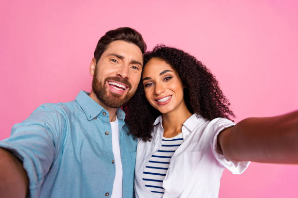 istock Happy young couple taking selfie in bright studio setting with pink background 2191311366