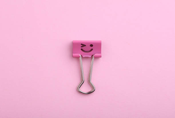 Binder clip with a smiling face on a pink background