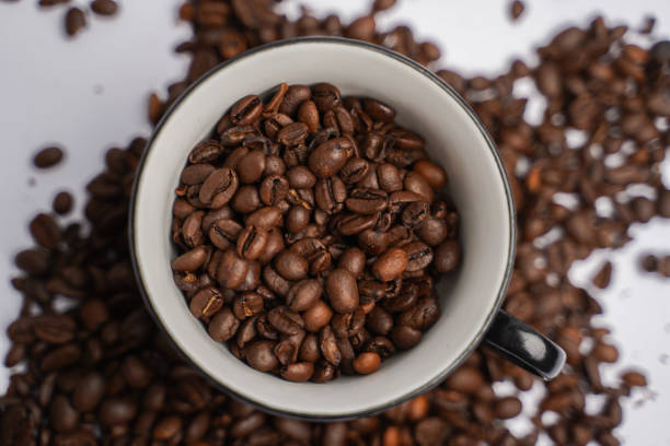 Coffee cup filled with beens. Beens background. Beens all over on a white background.