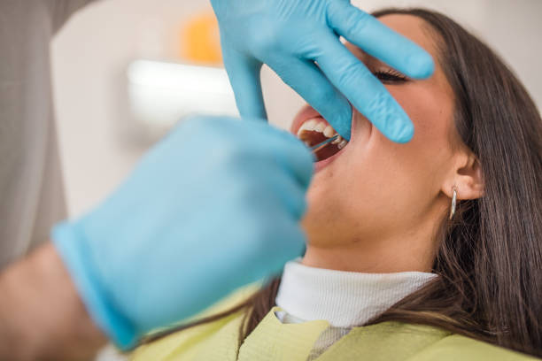 A dentist extracts a tooth from a female patient