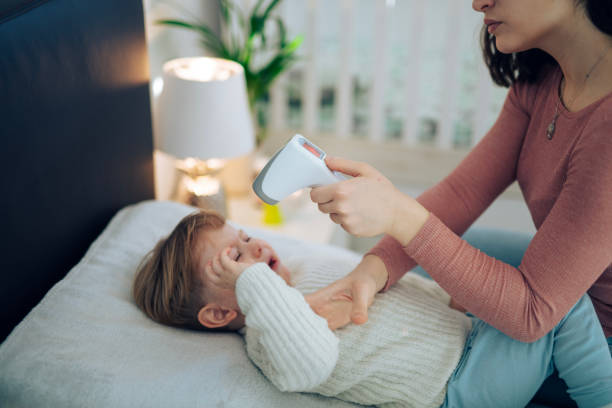 istock Concerned mother checking sick toddler's temperature at home. 2191313264