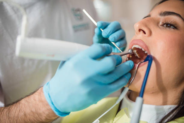 istock A male dentist wears protective gloves while fixing a patient's tooth 2191314077