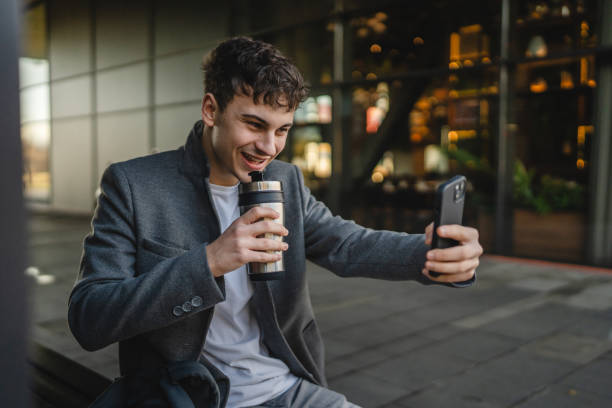 istock young man drink coffee sit on bench and have video call on cellphone 2191317752