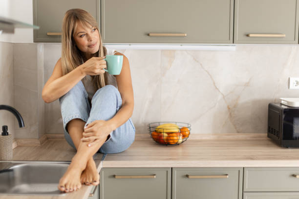 istock Beautiful woman sitting on a kitchen counter and drinking coffee 2191320281