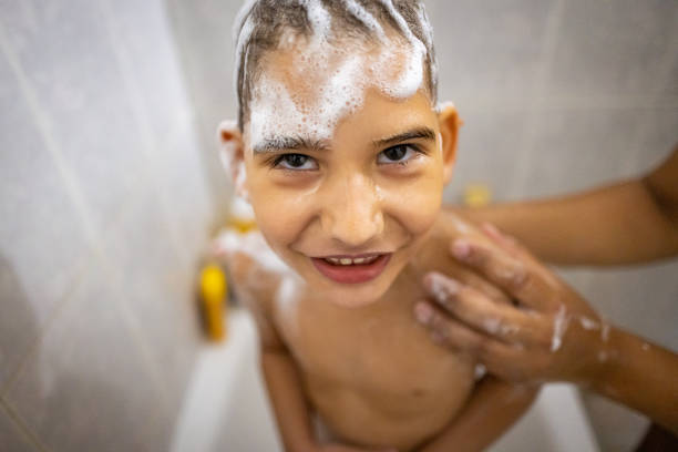 A boy smiles as his mother shampoos his hair, a heartwarming moment of care and cleanliness.