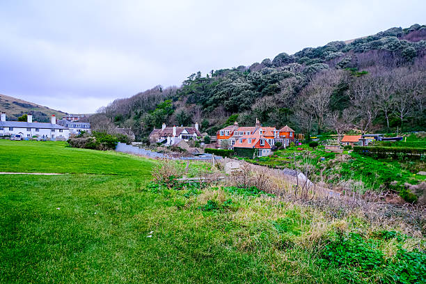 Lulworth Cove village view, Dorset, England, UK. Lulworth Cove and field view at winter cloudy cold day. Lulworth Cove bay, beach and cliffs view . The Jurassic Coast is a World Heritage Site on the English Channel coast of southern England. Dorset, UK.