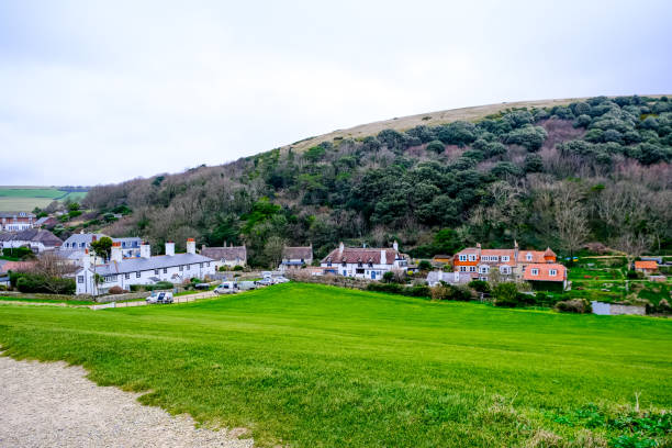 Lulworth Cove village view, Dorset, England, UK. Lulworth Cove and field view at winter cloudy cold day. Lulworth Cove bay, beach and cliffs view . The Jurassic Coast is a World Heritage Site on the English Channel coast of southern England. Dorset, UK.