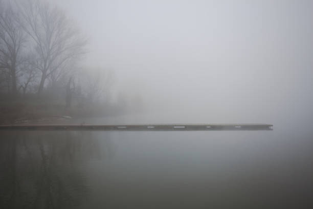 Piers next to a park by the lakeshore on a foggy morning in the italian countryside