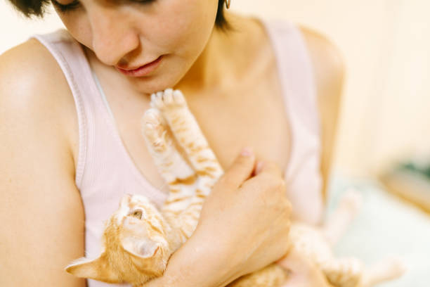 Young woman showing affection to a playful ginger kitten, enjoying a tender moment of companionship
