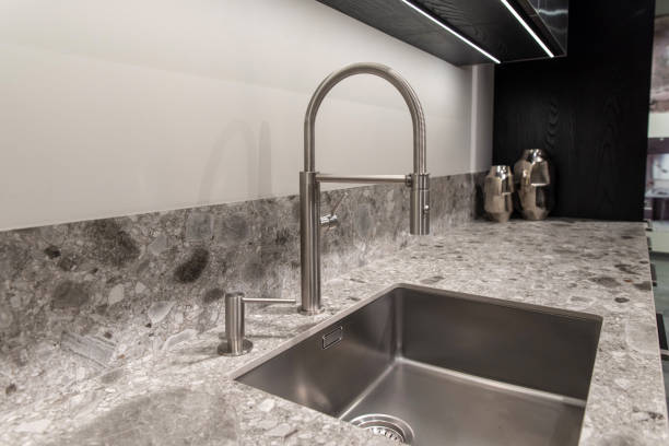 istock Modern curved stainless steel faucet installed in a gray kitchen workspace with soap dispenser 2191323359