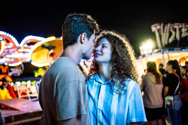 Happy young couple enjoying together at the amusement park at night