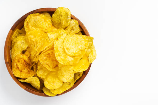istock Wooden bowl overflowing with golden potato chips on white background 2191325295