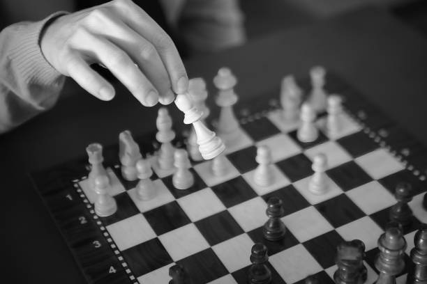 Woman making her move with a bishop into position on the chessboard. Black and White.