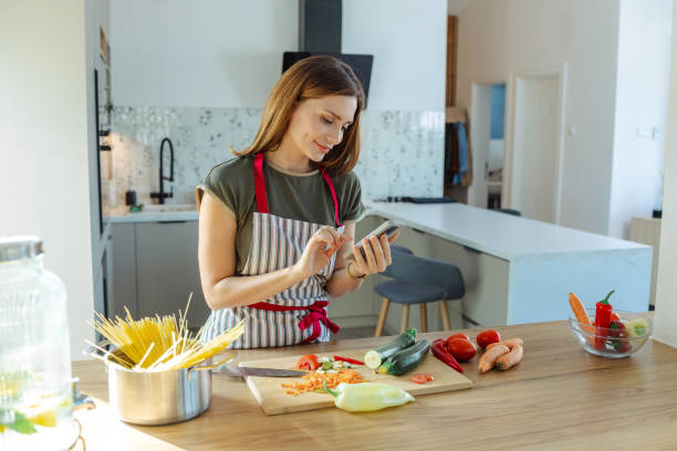 istock Woman using smartphone in modern kitchen while preparing fresh food 2191331914