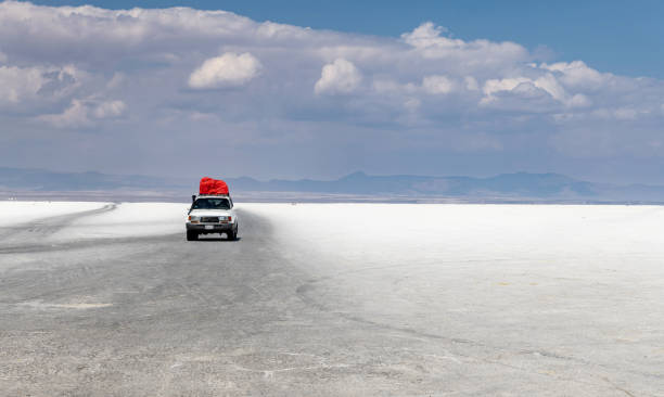 Colchani, Bolivia, October 18, 2023: A car drives on the Bolivian salt flats Salar de Uyuni on a sunny day.