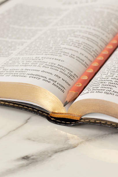 istock Open holy bible book with pencil on white marble table 2191334694