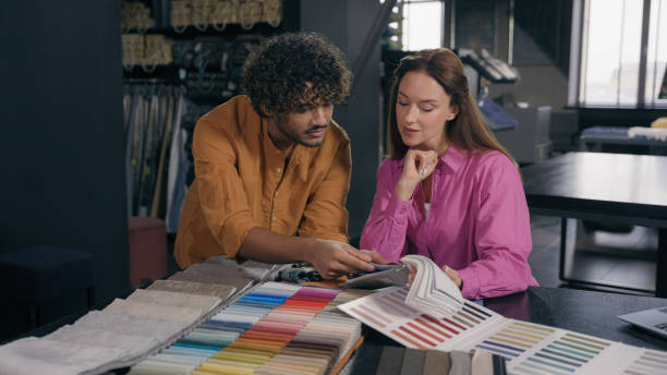 istock Multiracial couple clients customers looking textile samples discuss design ideas Arabian Indian man salesman Caucasian woman buyer choosing fabrics color for fashion clothes dressmaking in atelier 2191335716