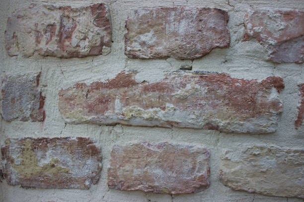 Detailed view of an aged brick wall with varying textures and colors, perfect for architectural or background purposes.