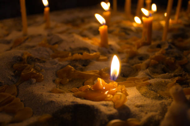 Detailed view of candles burning in low light, highlighting the texture of melted wax and warm glow. Suitable for concepts of spirituality and tranquility.