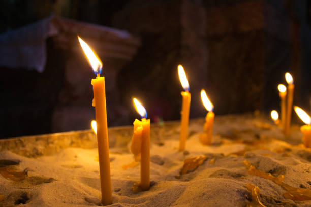 Detailed view of candles burning in low light, highlighting the texture of melted wax and warm glow. Suitable for concepts of spirituality and tranquility.