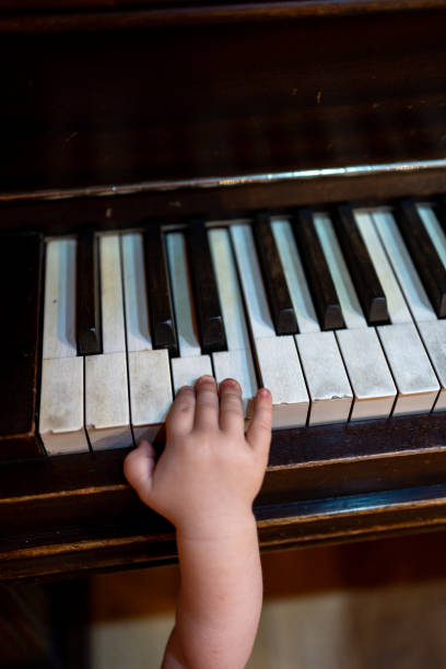 istock Child's hand touching piano keys, exploring music playfully indoors 2191347798